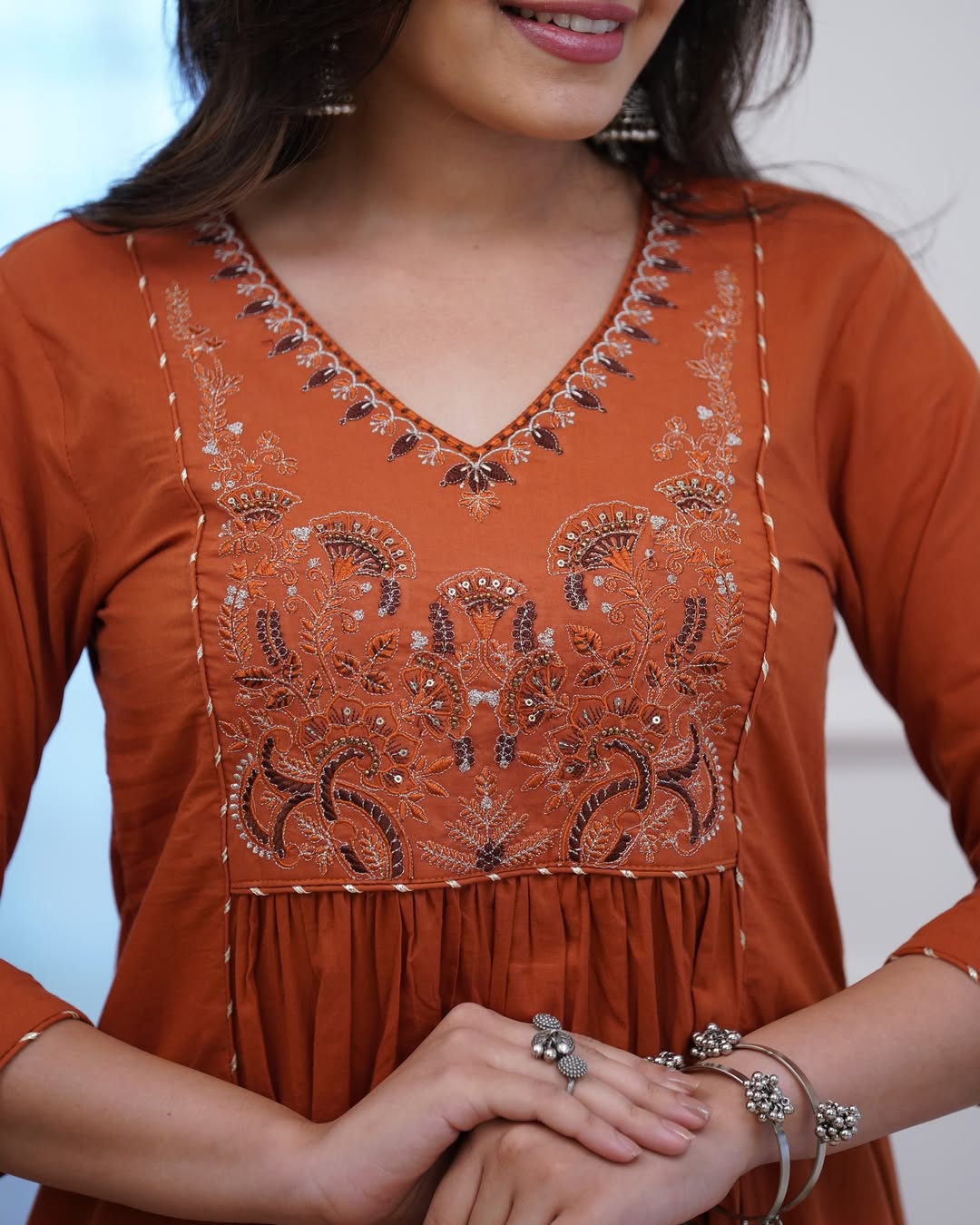 Close-up of a person wearing an orange embroidered dress with a blurred background
